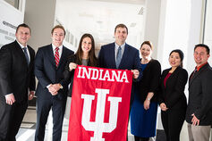 A group of students in business attire holding an IU flag.